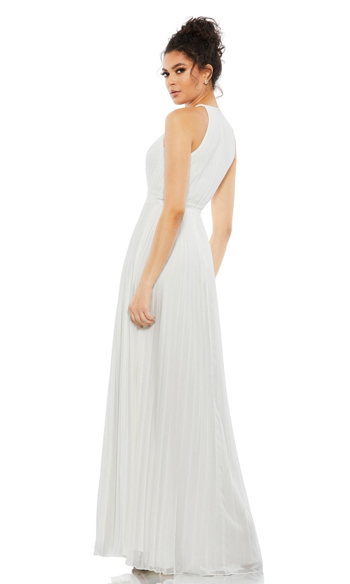 A woman models the Long Formal Dress 12496 by Mac Duggal—a sleeveless, floor-length pleated gown with an elegant silhouette—standing and glancing over her shoulder against a plain white backdrop.
